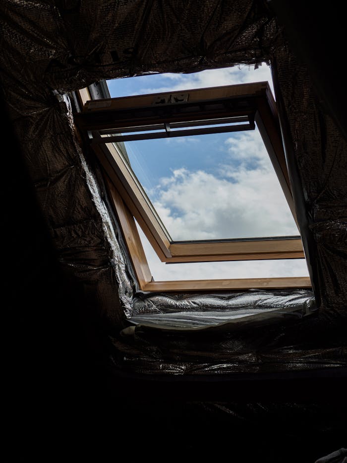 ours-journey A wooden attic window opens to reveal a clear blue sky and fluffy white clouds.