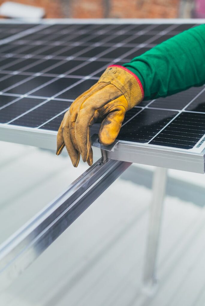 pexels photo 8853511 Close-up of a worker's hand in protective glove installing a solar panel.
